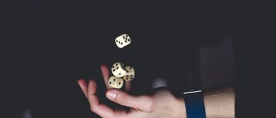 A close-up of a hand tossing several dice into the air against a dark background.