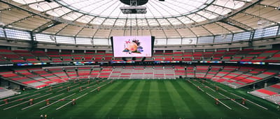 The interior of a massive, modern professional sports stadium with a high-tech roof and red seating.