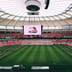 The interior of a massive, modern professional sports stadium with a high-tech roof and red seating.