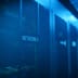 A row of modern server racks illuminated with blue light in a large data center.