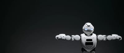 A sleek white humanoid robot with glowing blue eyes stands against a dark background.