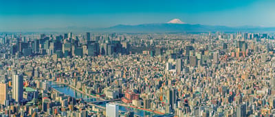 A sprawling panoramic view of the Tokyo city skyline on a clear day with Mount Fuji visible in the distance.