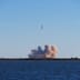 A powerful rocket launches into the sky over the ocean, leaving a thick plume of smoke in its wake.