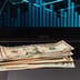 U.S. dollar bills resting on a modern laptop keyboard, symbolizing the digitization of traditional currency.