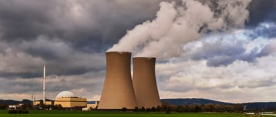 Cooling towers of a power plant emit plumes of steam under cloudy skies.