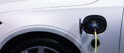 A close-up of a white electric vehicle plugged into a charging station.