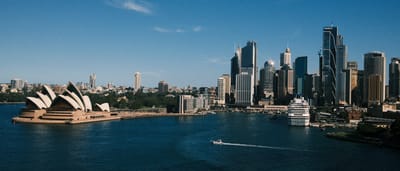 The Sydney skyline on a clear day, featuring the Opera House alongside the modern high-rises of the central business district.