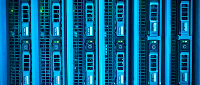 Rows of computer server racks illuminated with bright blue LED lights in a data center.