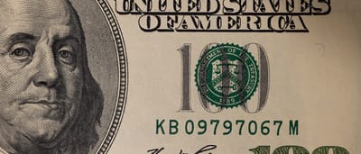A detailed close-up of a United States one hundred dollar bill featuring the portrait of Benjamin Franklin.
