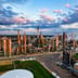 An aerial view of a sprawling energy refinery illuminated by the warm light of sunset.