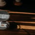 A glass sand timer sits on a wooden desk bathed in warm sunlight, casting long shadows.