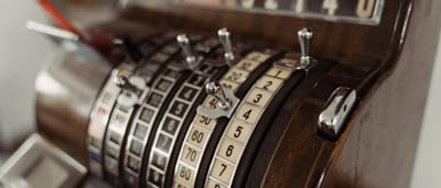 An extreme close-up of the brass mechanical keys and levers on a vintage cash register.