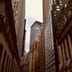 Looking up at the columned facade of the New York Stock Exchange and surrounding skyscrapers on Wall Street.