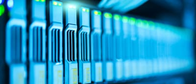 A row of illuminated server racks glowing with blue and green lights in a modern data center.