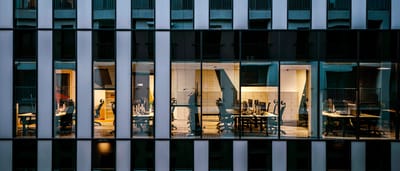 The illuminated windows of a modern corporate office building seen from the exterior at night.