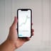 A hand holding a smartphone displaying a financial candlestick chart on a trading application.