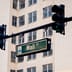 A street sign reading Wall St hanging next to a green traffic light in an urban setting.