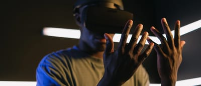 A man immersed in a virtual reality experience wearing a VR headset in a dark room with neon lights.