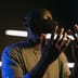 A man immersed in a virtual reality experience wearing a VR headset in a dark room with neon lights.