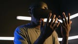 A man immersed in a virtual reality experience wearing a VR headset in a dark room with neon lights.