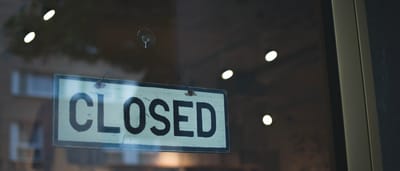 A simple closed sign hanging on the glass window of a modern storefront.