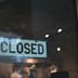 A simple closed sign hanging on the glass window of a modern storefront.