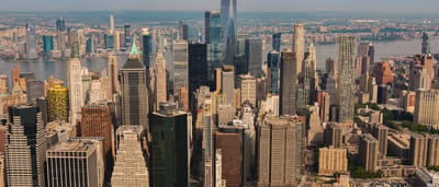 An aerial view of the New York City skyline featuring towering skyscrapers and the One World Trade Center.