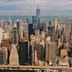 An aerial view of the New York City skyline featuring towering skyscrapers and the One World Trade Center.
