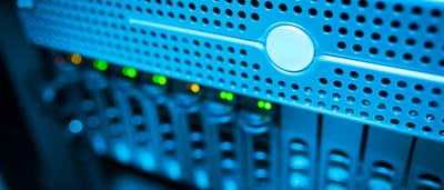 A close-up view of glowing indicators on a modern server rack in a blue-lit data center.