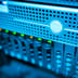 A close-up view of glowing indicators on a modern server rack in a blue-lit data center.
