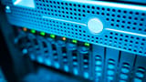 A close-up view of glowing indicators on a modern server rack in a blue-lit data center.