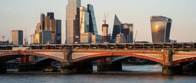 The modern skyscraper skyline of the City of London financial district glowing in warm sunlight.