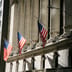 American flags hang between the grand stone columns of the New York Stock Exchange facade.