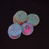 A stack of physical gold Bitcoin tokens sitting in heavy shadow against a pitch-black background.
