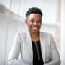 A confident businesswoman smiles warmly in a bright, modern office space.