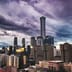 Modern skyscrapers rise against a dark, stormy sky in Beijing's central business district.