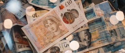 A close-up view of British five and ten pound notes illuminated by warm lighting.