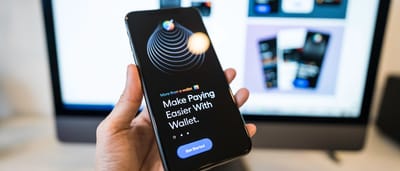 A hand holding a smartphone that displays a digital wallet and banking app interface.