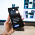 A hand holding a smartphone that displays a digital wallet and banking app interface.