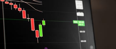 A close-up of a digital screen displaying a stock market chart with red candlesticks indicating a downward trend.