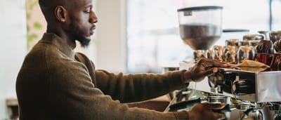 A barista expertly brews coffee on an espresso machine in a warm, inviting cafe environment.