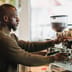 A barista expertly brews coffee on an espresso machine in a warm, inviting cafe environment.