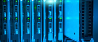 A close-up view of a glowing blue server rack component being adjusted in a modern data center.