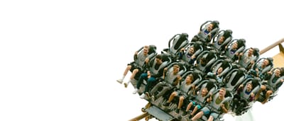 Passengers scream as they plunge down a steep roller coaster drop against a stark white sky.