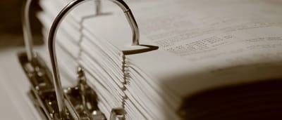 A thick, open binder filled with dense printed documents and administrative paperwork.