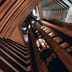 A glowing glass elevator ascends through the center of a towering, geometric modern atrium.