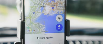 A close-up of a smartphone on a car mount displaying the Google Maps application and tracking a location.