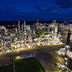 A dramatic aerial view of an illuminated oil refinery operating at night.