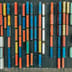 An aerial top-down view of brightly colored shipping containers arranged in straight, chart-like rows at a logistics hub.