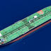 An aerial top-down view of a large green oil tanker sailing across deep blue ocean waters.
